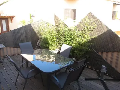 a patio with a table and chairs on a deck at MARE BELLU AGOSTA PLAGE in Albitreccia
