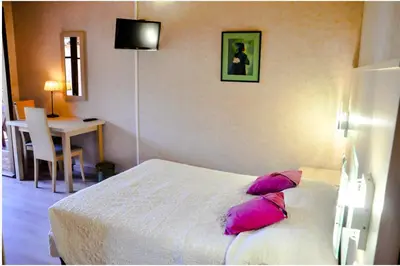 a bedroom with a bed with pink pillows and a table at Résidence Stella Marina in Serriera