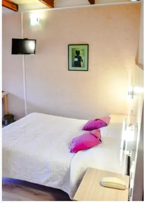 a bedroom with a white bed with pink pillows at Résidence Stella Marina in Serriera