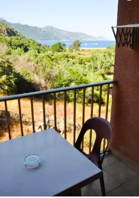 a white table and chair on a balcony with a view at Résidence Stella Marina in Serriera