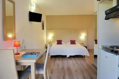 a bedroom with a bed and a table and a desk at Résidence Stella Marina in Serriera
