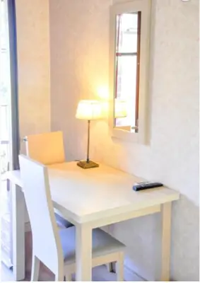 a table with a lamp and two white chairs and a table with a lamp at Résidence Stella Marina in Serriera