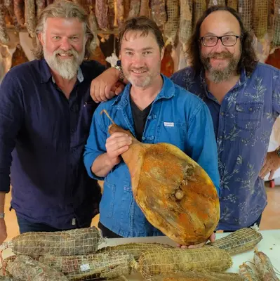 three men standing next to a table with a large animal at U San Larenzu in Aullène