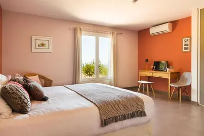 a bedroom with a bed and a window and a desk at Le Ruone in Calcatoggio