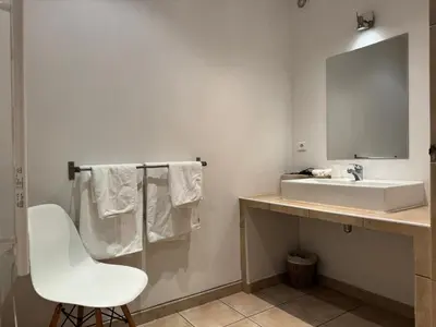 a bathroom with a white sink and a white chair at Le Ruone in Calcatoggio