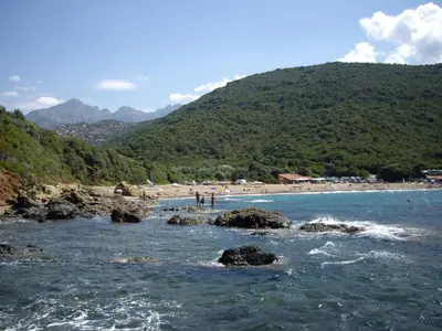 a beach with a group of people standing on the rocks at Les Asphodèles in Partinello