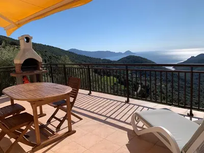 a balcony with a table and chairs and a view of the ocean at Les Asphodèles in Partinello