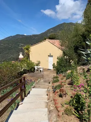 a house with a table and a fence and flowers at Les Asphodèles in Partinello