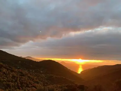 a sunset in the mountains with the sun setting at Les Asphodèles in Partinello