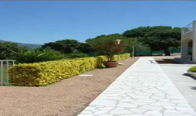 a walkway next to a building with bushes and trees at Résidence Dicieppo in Ajaccio