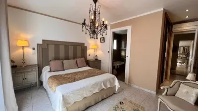 a bedroom with a large bed and a chandelier at Chez Virginie in Porto-Vecchio
