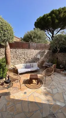 a patio with a couch and tables and a stone wall at Chez Virginie in Porto-Vecchio