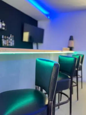 a row of green chairs in a bar at Residence Canella in Sari Solenzara