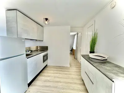 a kitchen with white cabinets and a wooden floor at Residence Canella in Sari Solenzara