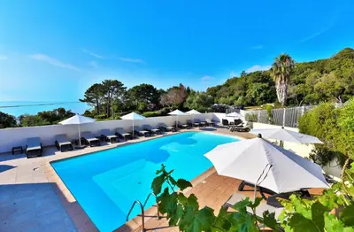 a resort pool with umbrellas and chairs at Residence Canella in Sari Solenzara