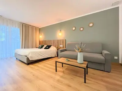 a bedroom with a bed and a couch and a table at Auberge les Oliviers in Lucciana