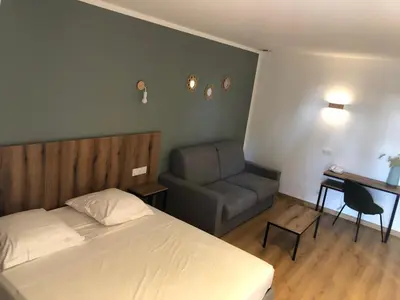 a bedroom with a bed and a chair and a desk at Auberge les Oliviers in Lucciana