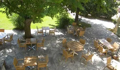 a group of tables and chairs and a tree at Auberge les Oliviers in Lucciana