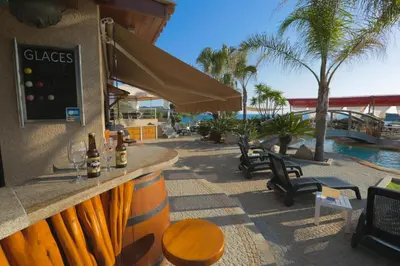 a bar with a table and chairs next to a pool at Résidence & SPA Marina d'Arone in Piana