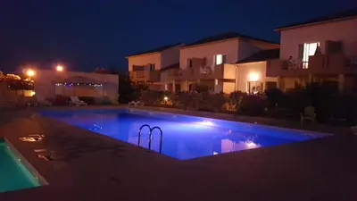 a swimming pool in front of a house at night at Bel appartement confortable et cosy en résidence avec piscine à 5 mn de la mer in Linguizzetta