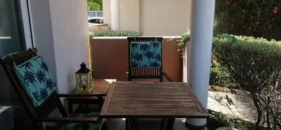 a wooden table and two chairs on a porch at Bel appartement confortable et cosy en résidence avec piscine à 5 mn de la mer in Linguizzetta