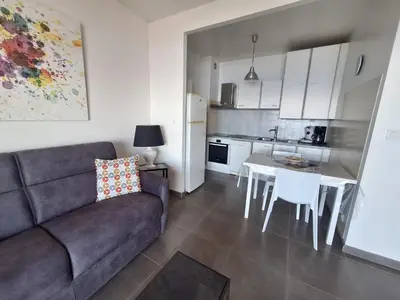 a living room with a couch and a table and a kitchen at Le Parc Impérial in Ajaccio