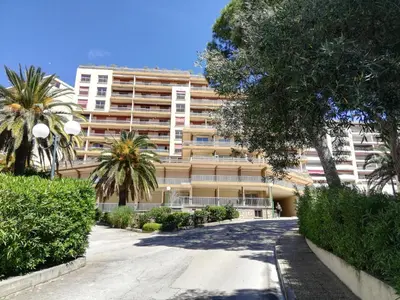 an apartment building with palm trees in front of it at Le Parc Impérial in Ajaccio