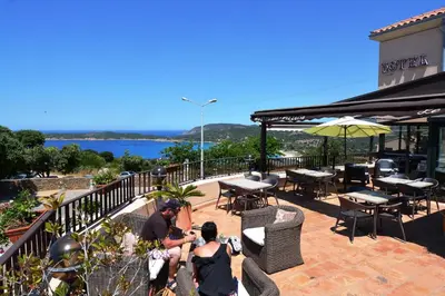 a group of people sitting on a patio overlooking the water at Hotel & Restaurant le Saint Jean in Cargèse