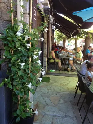 a group of people sitting at an outdoor restaurant at Hotel & Restaurant le Saint Jean in Cargèse