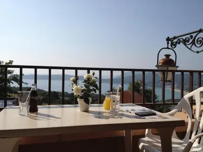 a table on a balcony with a view of the ocean at Hotel & Restaurant le Saint Jean in Cargèse