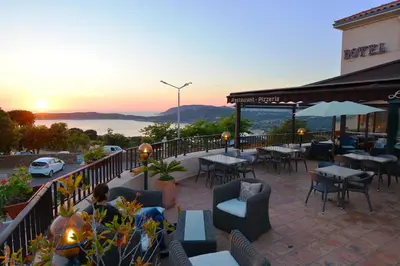 a restaurant with tables and chairs and the sunset at Hotel & Restaurant le Saint Jean in Cargèse