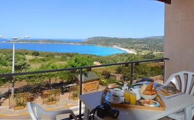 a balcony with a table and a view of a beach at Hotel & Restaurant le Saint Jean in Cargèse