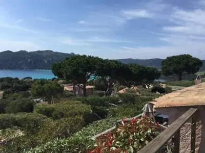 a balcony with a view of the water and trees at Les Mini-Villas de Santa Giulia in Porto-Vecchio