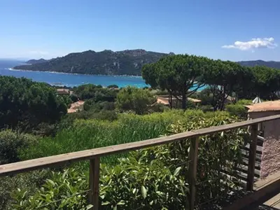 a wooden balcony with a view of the ocean at Les Mini-Villas de Santa Giulia in Porto-Vecchio