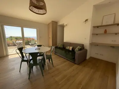 a living room with a table and chairs and a couch at Les Mini-Villas de Santa Giulia in Porto-Vecchio