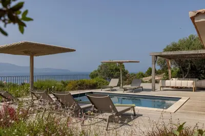 a pool with chairs and umbrellas on a deck at Résidence La Plage in Propriano