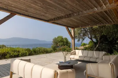 a patio with white chairs and a wooden pergola at Résidence La Plage in Propriano