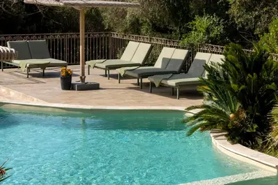 a row of lounge chairs next to a swimming pool at Résidence La Plage in Propriano
