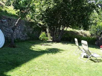 two chairs sitting in the grass near a stone wall at CASA PENTONE in Cervione