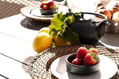 a table topped with a bowl of strawberries and lemons at Résidence I Levri in Porto-Vecchio