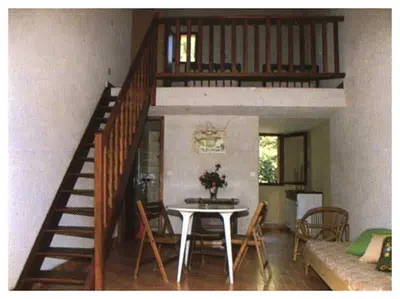 a living room with a table and a staircase at Domaine de l'Avidanella in Santa-Lucia-di-Moriani