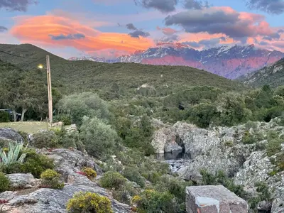 a sunset over the mountains with a river and trees at Au pont de Tuarelli, Ludique, Galeria, Corse in Manso