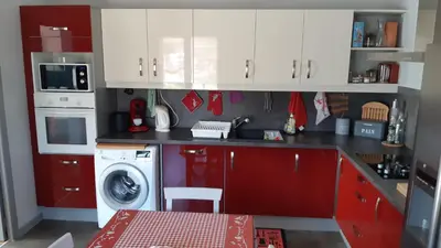 a kitchen with red cabinets and a washing machine at Au pont de Tuarelli, Ludique, Galeria, Corse in Manso