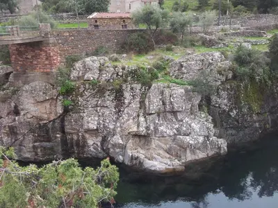 a bridge over a river next to a rock wall at Au pont de Tuarelli, Ludique, Galeria, Corse in Manso