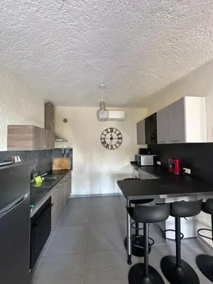 a kitchen with a table and a clock on the wall at CARDELLINI 23 in Sari Solenzara