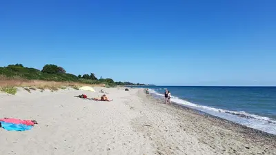 a beach with people laying on the sand and the water at OSARI - MORIANI plage in Moriani Plage