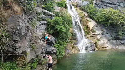 two men standing in the water near a waterfall at OSARI - MORIANI plage in Moriani Plage