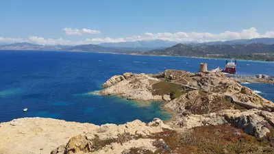 a lighthouse on a rocky island in the ocean at OSARI - MORIANI plage in Moriani Plage