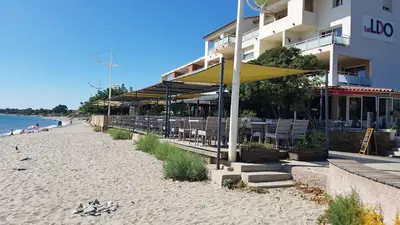 a beach with chairs and umbrellas next to a building at OSARI - MORIANI plage in Moriani Plage