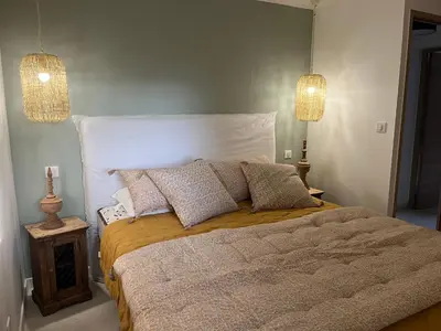 a bedroom with a large bed with pillows and two lights at Maison Le Citronnier avec piscine - Domaine E Case Di Cuttoli in Cuttoli-Corticchiato